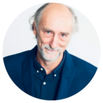 Man with grey hair wearing dark blue shirt and blazer.