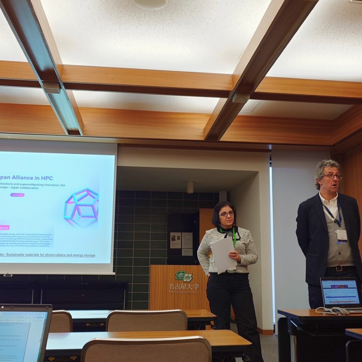 A man presenting a talk about the HANAMI project standing in front of a screen and a woman behind him.