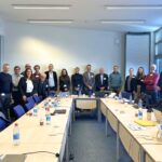 Group of people standing in a large room.