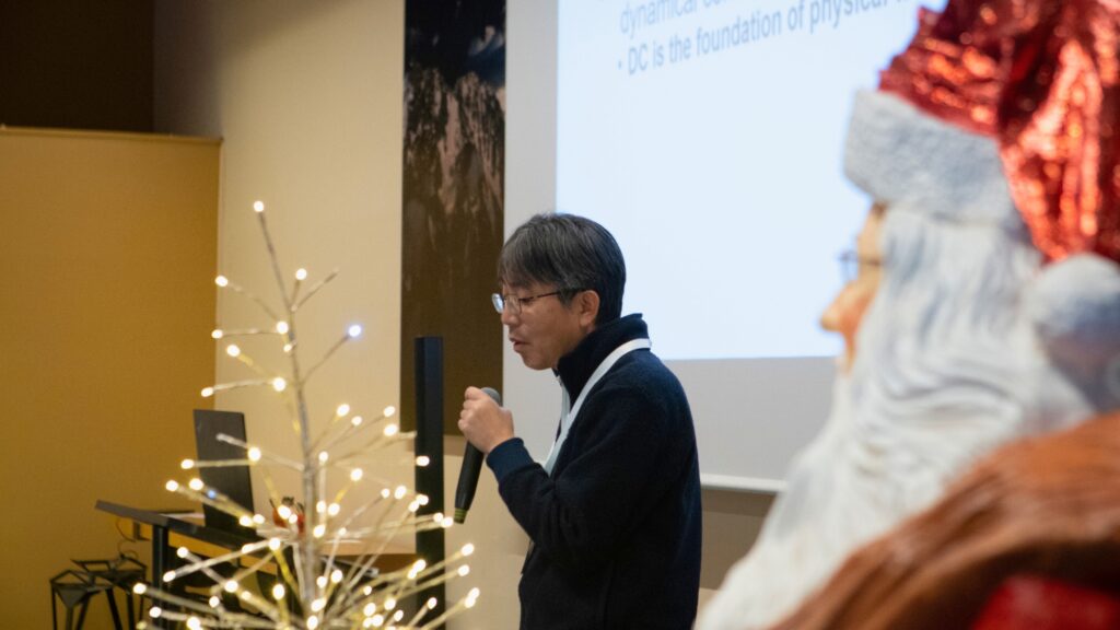 Man talking to a microphone with slides in the background showing scientific visualisations related to climate.