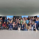 Large group photo of participants at the ACM Asian School inside a data centre in front of server racks, wearing event badges and posing together.