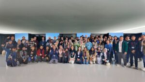 Large group photo of participants at the ACM Asian School inside a data centre in front of server racks, wearing event badges and posing together.